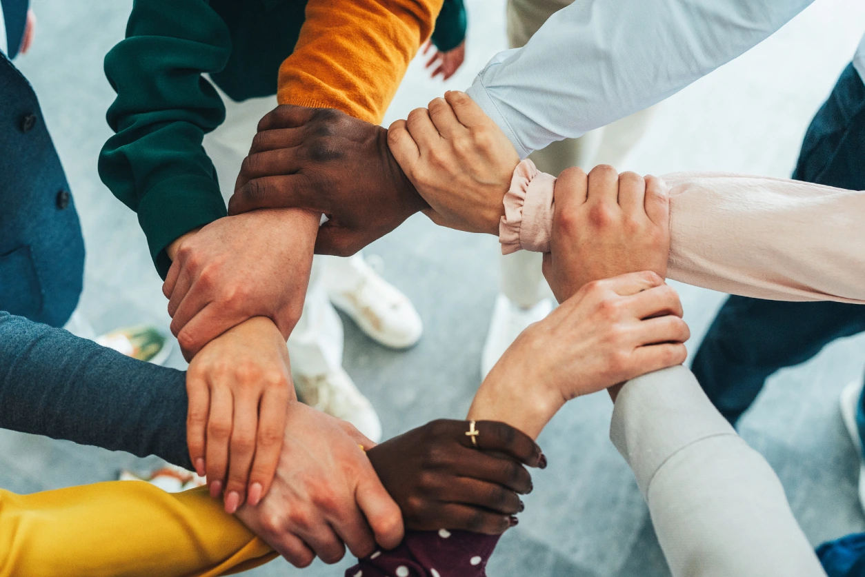 Diverse hands joined in a unity circle.